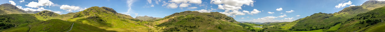 Panoramic view of green landscape and mountains against sky
