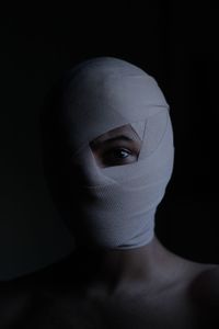 Portrait of woman face wrapped with bandage against black background