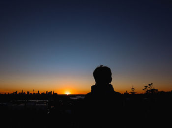 Silhouette people by cityscape against clear sky during sunset