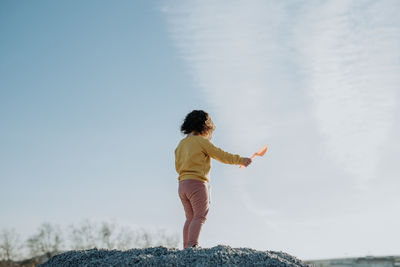 Rear view of man standing on rock against sky