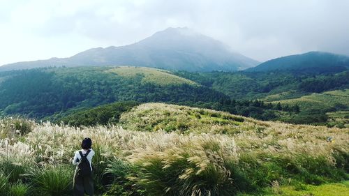 Rear view of woman standing on landscape against mountain