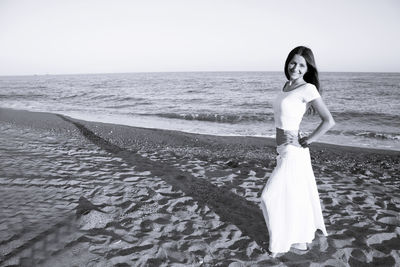 Woman dressed in white barefoot on the beach sand. smiling