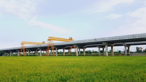View of bridge over field against sky