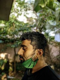 Portrait of young man standing against tree