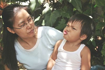 Mother looking at son making face in park