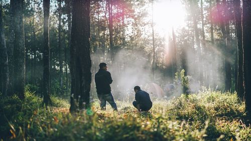 Silhouette people against trees in forest