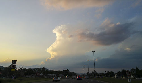 Cars on road against cloudy sky