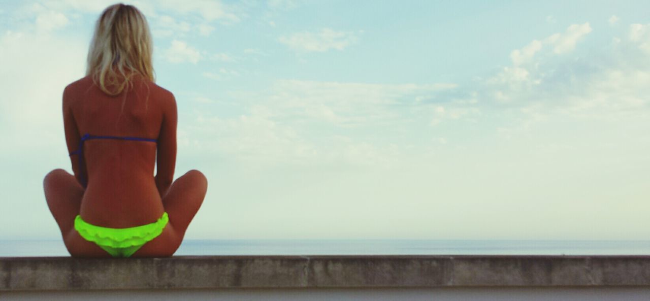 sky, horizon over water, sea, lifestyles, leisure activity, holding, cloud - sky, standing, water, rear view, person, cloud, day, outdoors, beach, nature, waist up, tranquility