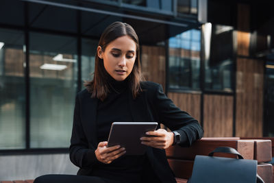 Young woman using mobile phone while sitting on table