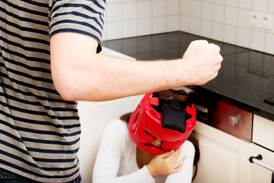 Midsection of man holding woman standing against wall