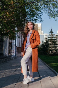 Portrait of young woman standing on footpath