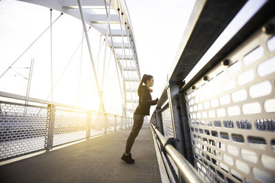 Side view of woman standing on bridge