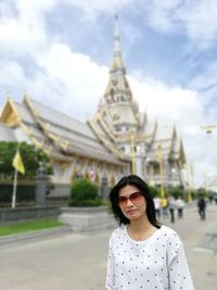 Portrait of mature woman wearing sunglasses standing against temple