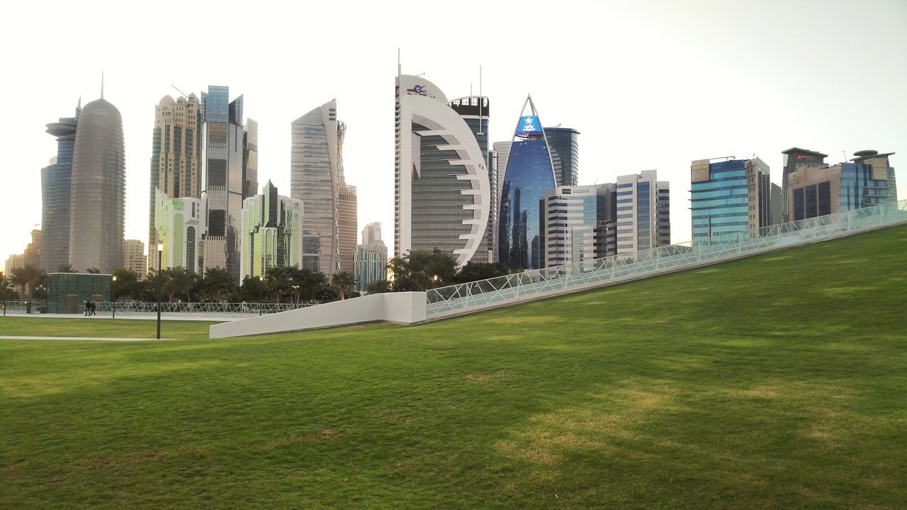 architecture, building exterior, city, modern, grass, built structure, skyscraper, lawn, green color, no people, growth, luxury, clear sky, outdoors, urban skyline, tree, sky, apartment, downtown district, travel destinations, day, futuristic, cityscape