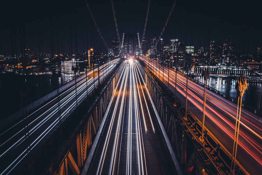 HIGH ANGLE VIEW OF LIGHT TRAILS ON ROAD AGAINST BUILDINGS