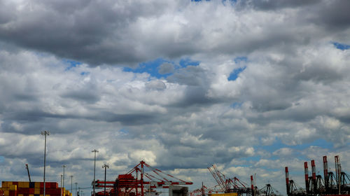 Low angle view of cranes in city against sky