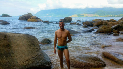 Portrait of shirtless man standing at beach