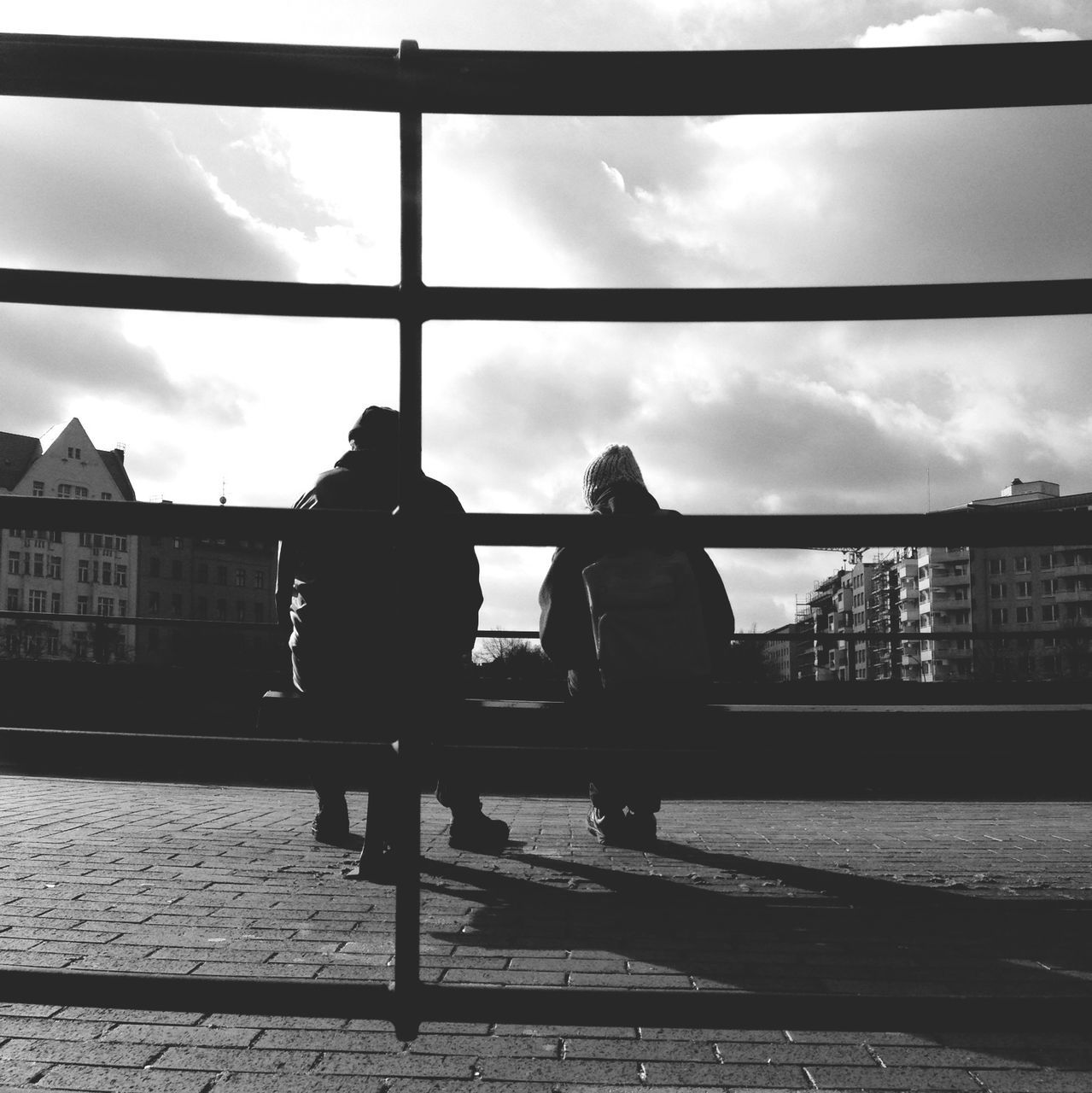 architecture, building exterior, sky, built structure, cloud - sky, men, lifestyles, railing, city, leisure activity, cloud, person, standing, walking, city life, silhouette, full length