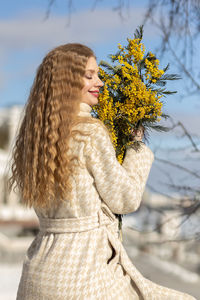 A woman with a bouquet of acacia flowers. the concept of the spring - march 8, easter, women's day.