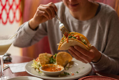 Midsection of woman having food at home