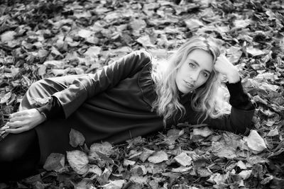 Portrait of smiling young woman lying on autumn leaves at park