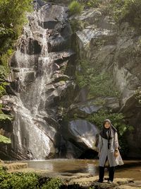 Portrait of smiling standing against waterfall
