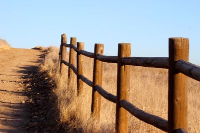 Wooden fence on field against clear sky