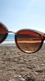 Close-up of sunglasses on beach against sky