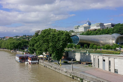 Buildings by river against sky in city