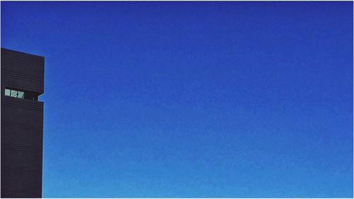 Low angle view of trees against clear blue sky