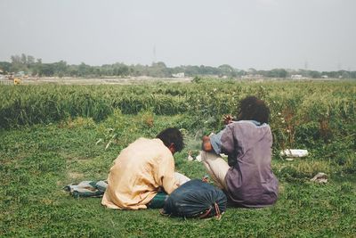 Rear view of people on field against clear sky