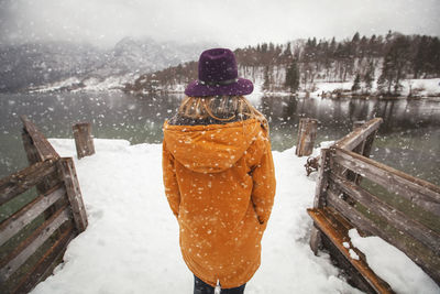 Rear view of woman on pier in lake during winter