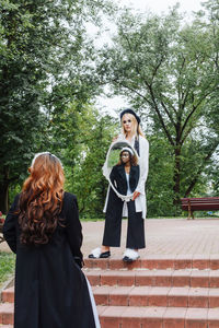 Full length of woman holding while standing against trees