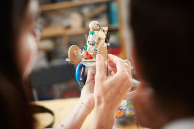 Cropped image of mature female engineer holding model at workshop