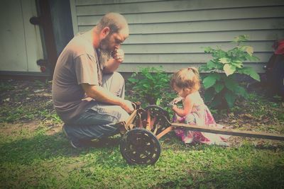 Father and daughter crouching on field at backyard