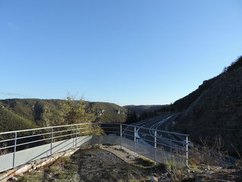 Bridge over mountain against clear blue sky