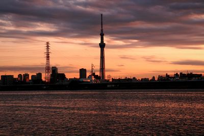 Communications tower against cloudy sky at sunset