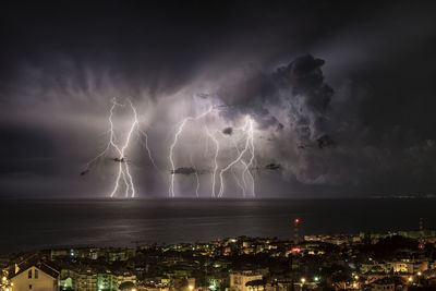 Lightning over illuminated cityscape against sky at night