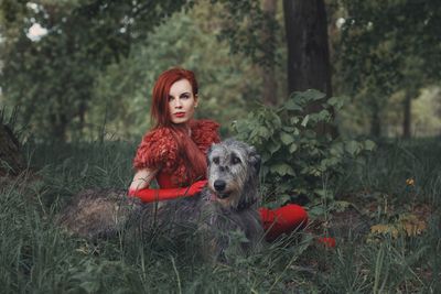 Portrait of young woman with dog against trees