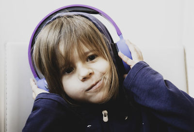 Close-up portrait of cute girl listening music through headphones