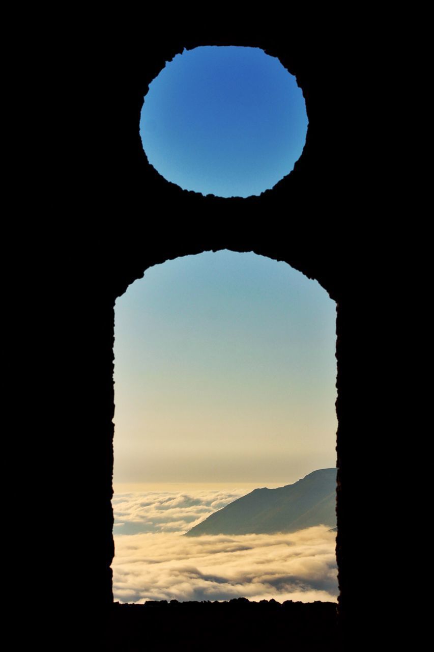 SILHOUETTE ARCH AGAINST CLEAR SKY DURING SUNSET SEEN THROUGH WINDOW