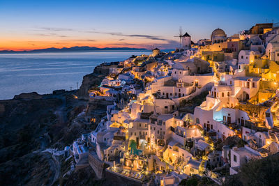 High angle view of townscape by sea against sky at sunset