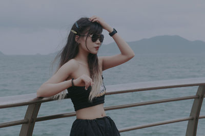 Side view of young woman looking at binoculars at beach