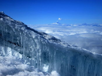 Icicles on rock against cloudscape