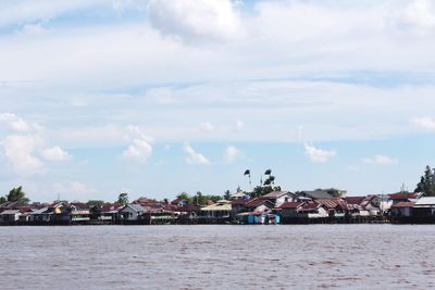 Buildings by sea against sky