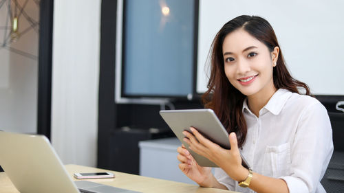 Portrait of young woman using laptop at table