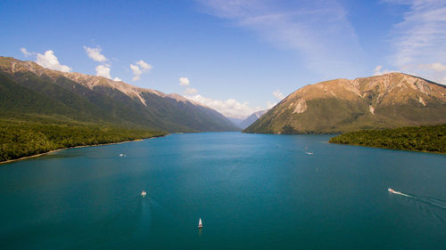 Scenic view of sea by mountains against blue sky