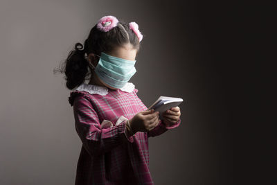 Full length portrait of girl standing against black background