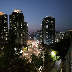Illuminated buildings in city against clear sky at night
