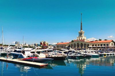 Sailboats moored at harbor against clear blue sky